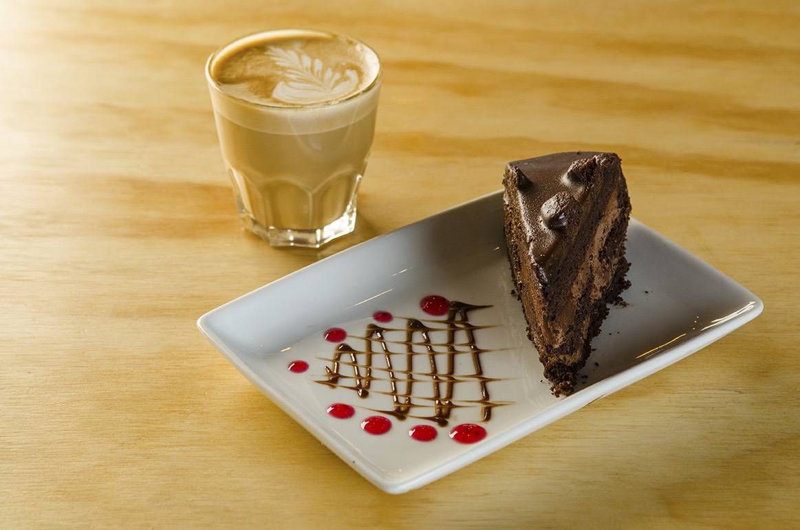 Porción de torta de chocolate con capas de relleno y cobertura brillante